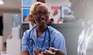 Idaho medical assistant smiling and discussing treatment with patient in clinic